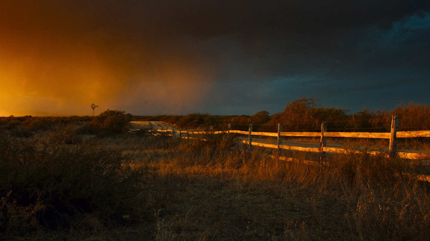 Sunrise over North Texas ranch country, mesquite brush and a dirt two-track road between barbed wire fence lines